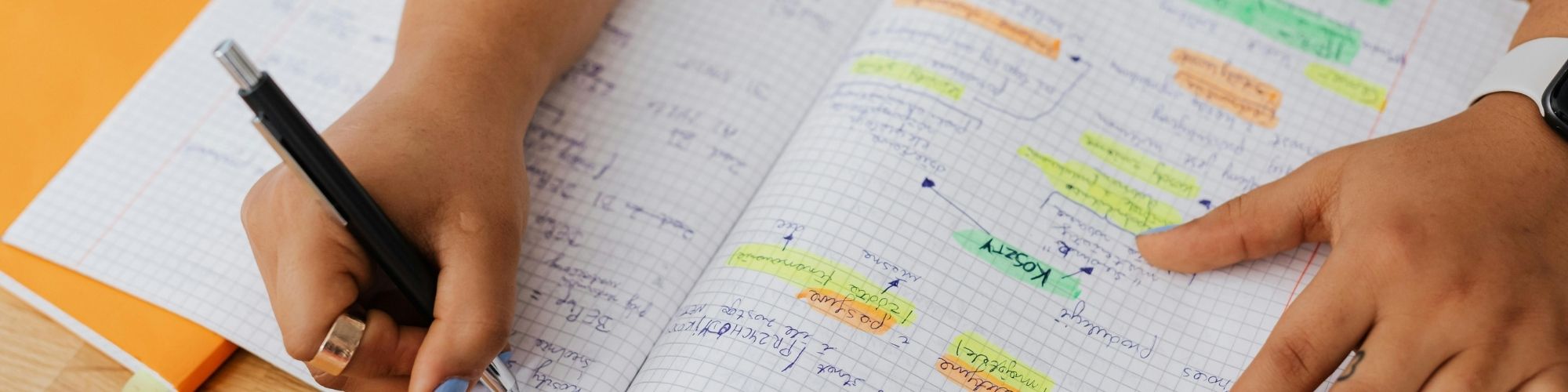 Étudiant de la HE2B assis avec un cahier, en réflexion sur son parcours.